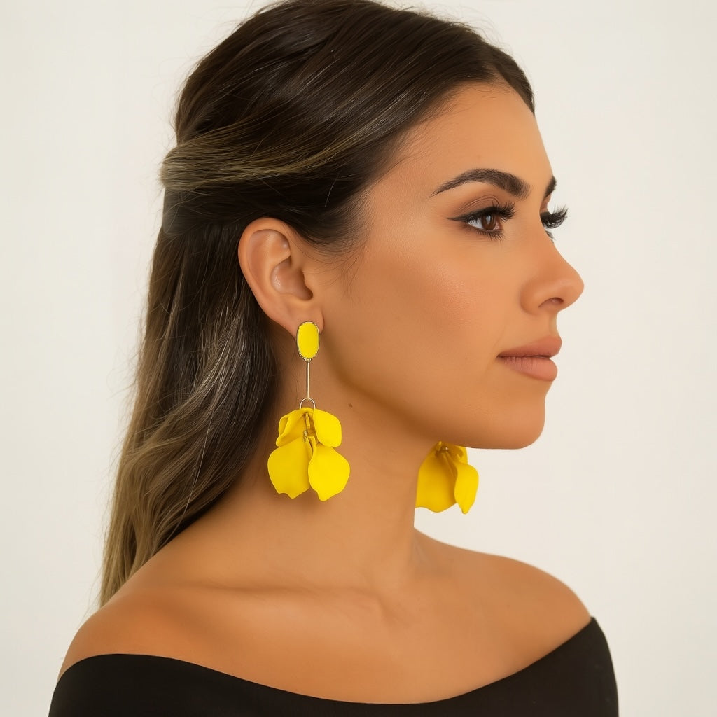 Woman wearing yellow floral earrings against a plain background
