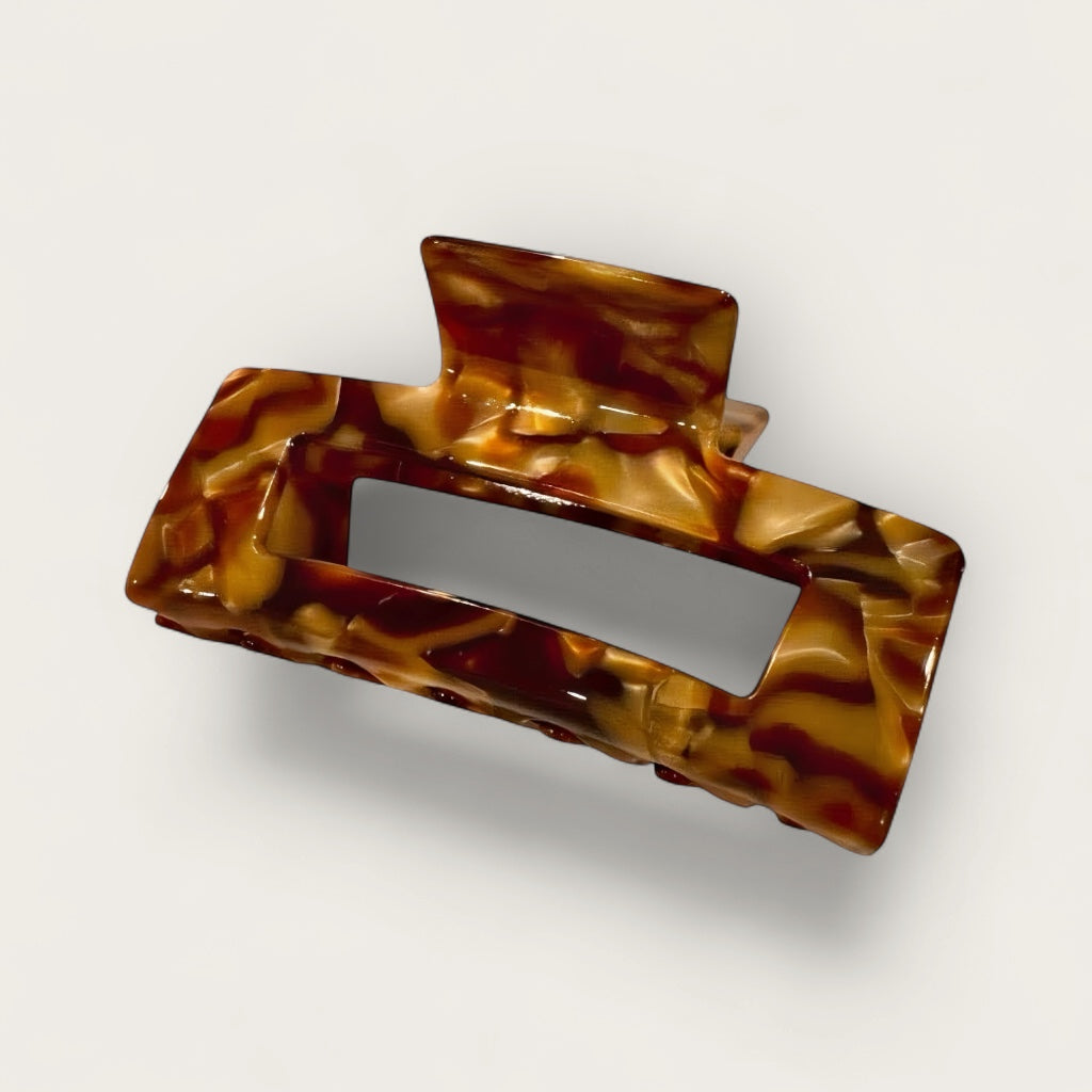 Amber glaze tortoise sculpted hair claw clip on soft white, grey background.