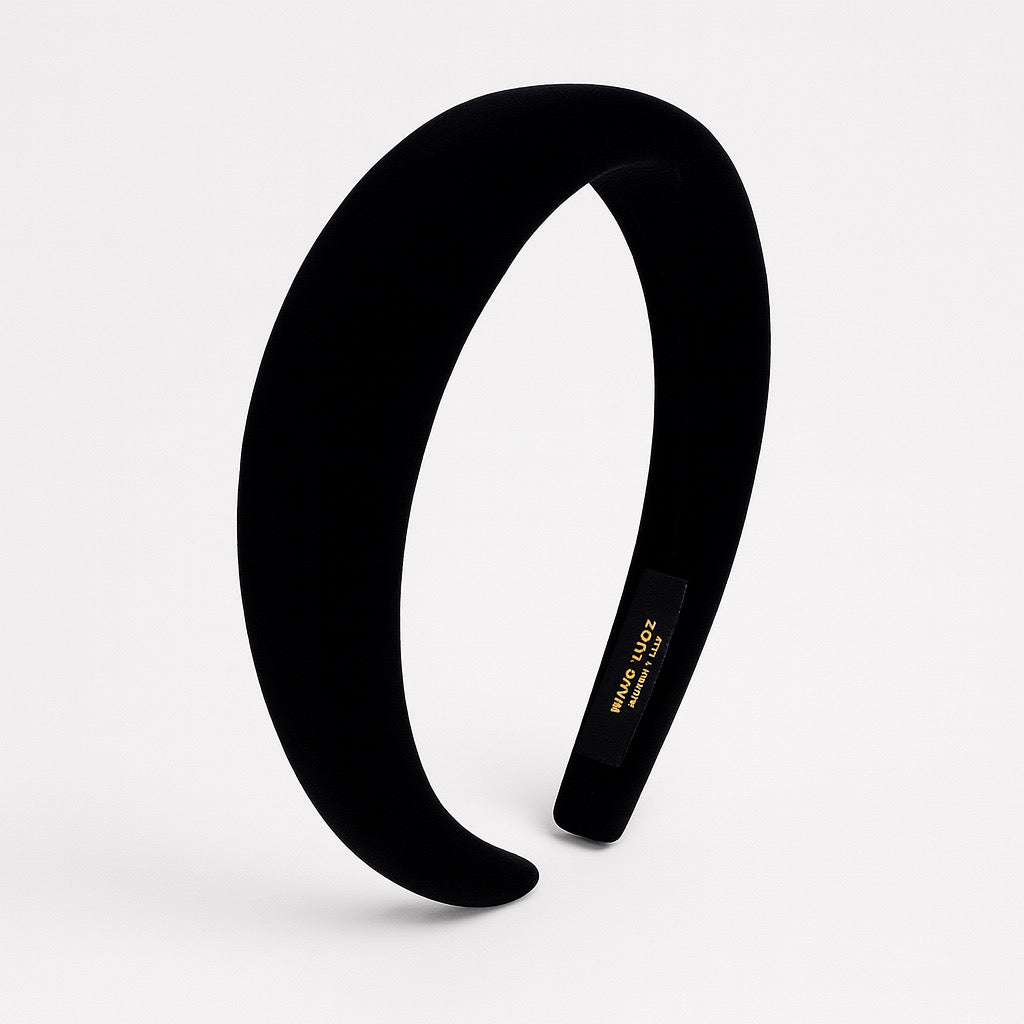 Elegant black velvet headband photographed from the side on light background.