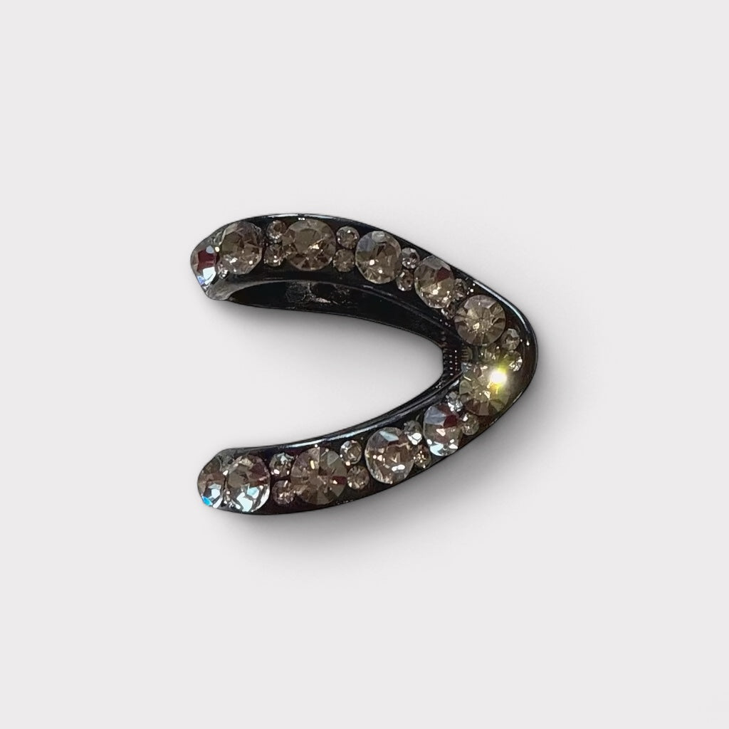 Small black hair claw clip with champagne crystals on white background.