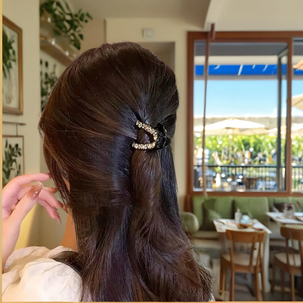 Model with long brown hair wearing the crystal hair claw in a cafe setting.