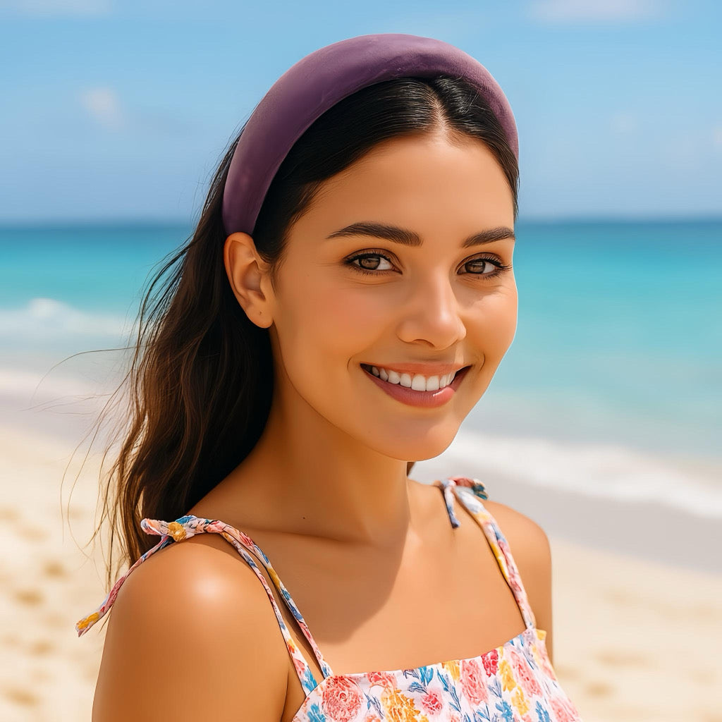 Smiling woman wearing a lavender velvet headband on a bright summer day by the beach.