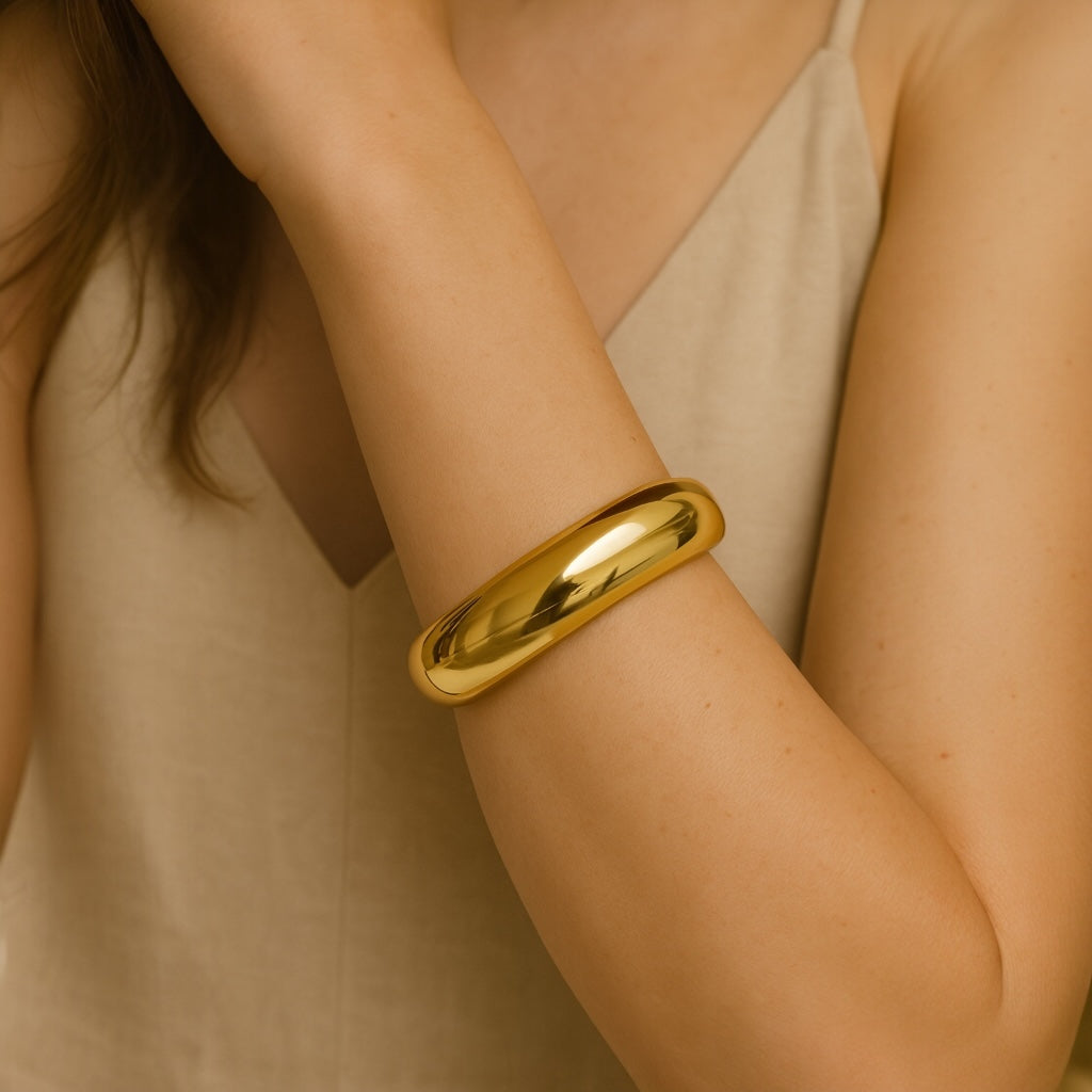 Model wearing PaulaB 18k gold-plated stainless-steel cuff bracelet with neutral outfit - timeless chic and polished accessory.