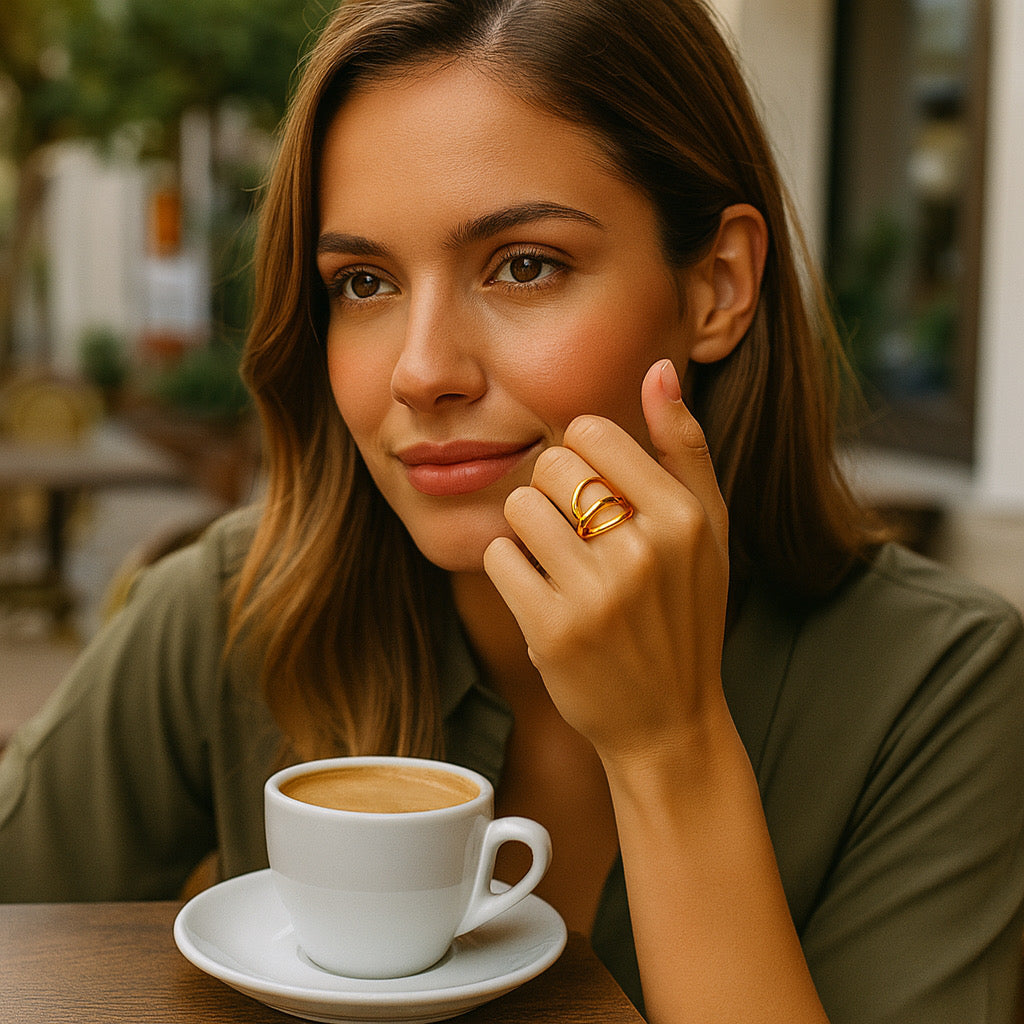 Model wearing PaulaB 18k gold-plated open curve ring at cafe - everyday lifestyle elegance jewelry photo.