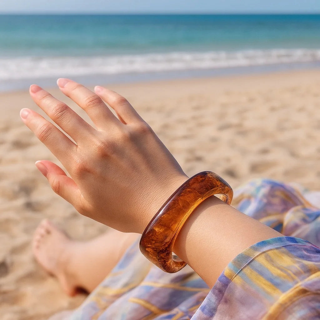 PaulaB amber resin bangle worn at the beach - open hand lifestyle shot. Perfect summer jewellery for Australia, NZ, UK.