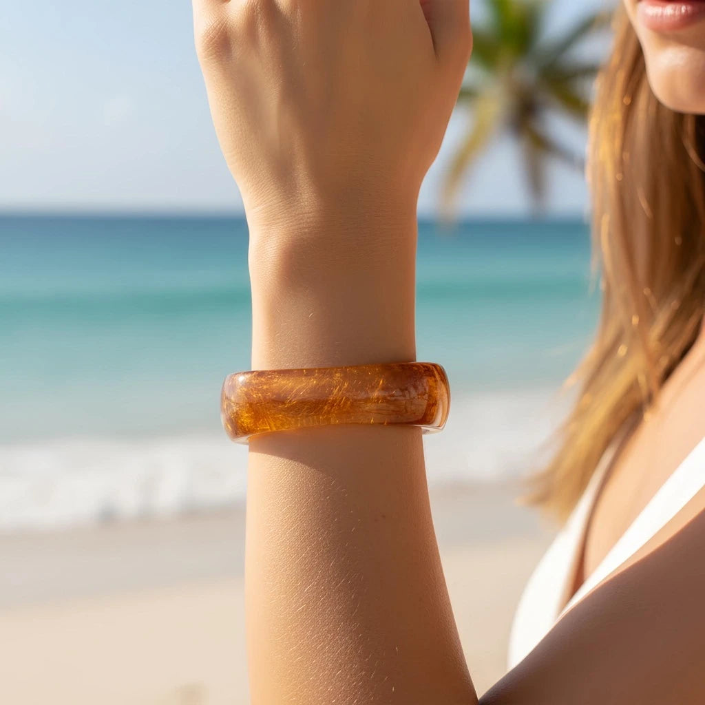 Close-up of arm wearing PaulaB amber in beach sunlight. Coastal fashion Australia, NZ, UK.