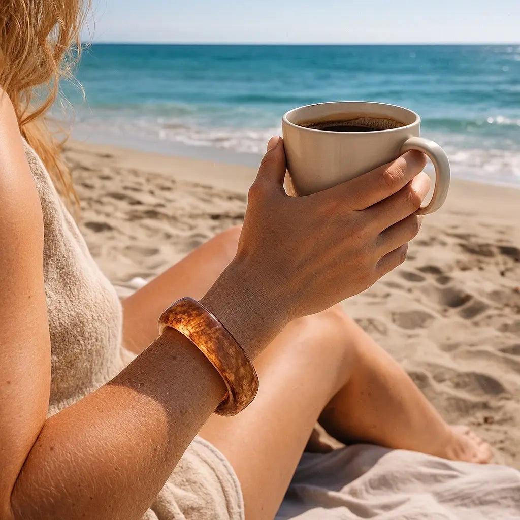 Beach lifestyle coffee moment with PaulaB amber resin bangle. Summer accessories Australia, NZ, UK.