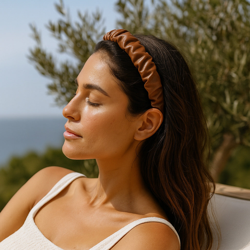 PaulaB Chocolate Brown elegance leather ruched headband worn by a model in a relaxing holiday outdoor setting.