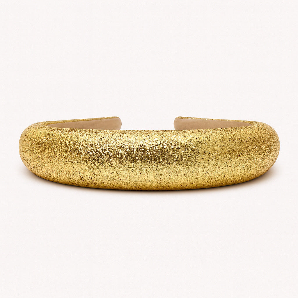 Closeup texture of PaulaB gold padded headband with shimmering glitter finish.