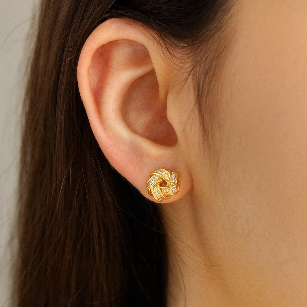 Model wearing 14k gold love-knot zircon stud earrings, close-up.