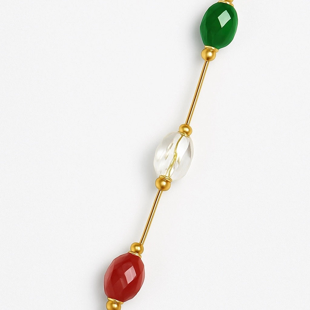 Close-up pf Paulab-gold-plated necklace showcasing colorful faceted gemstones red, green, blue, purple and clear stones.