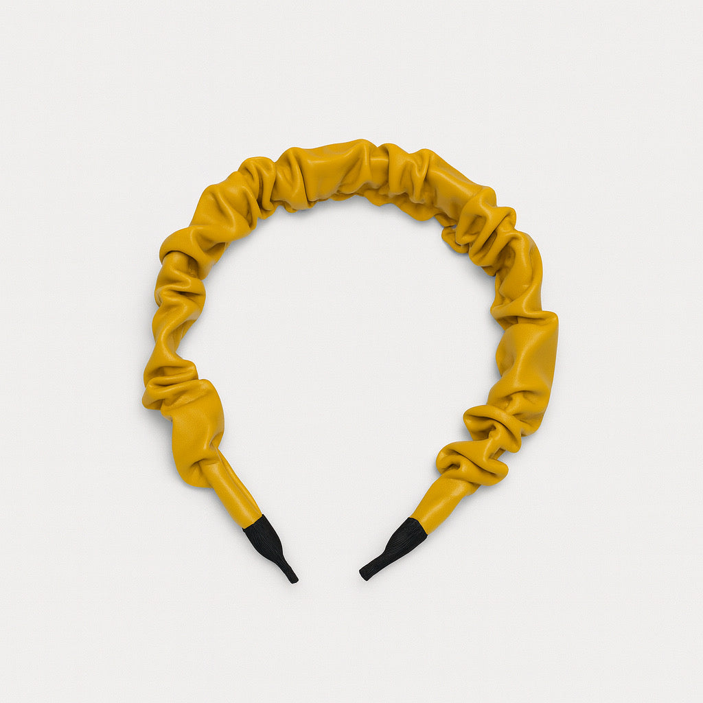 Top flat lay view of PaulaB mustard yellow PU leather ruched headband on white background, showing overall round shape and ruched texture.