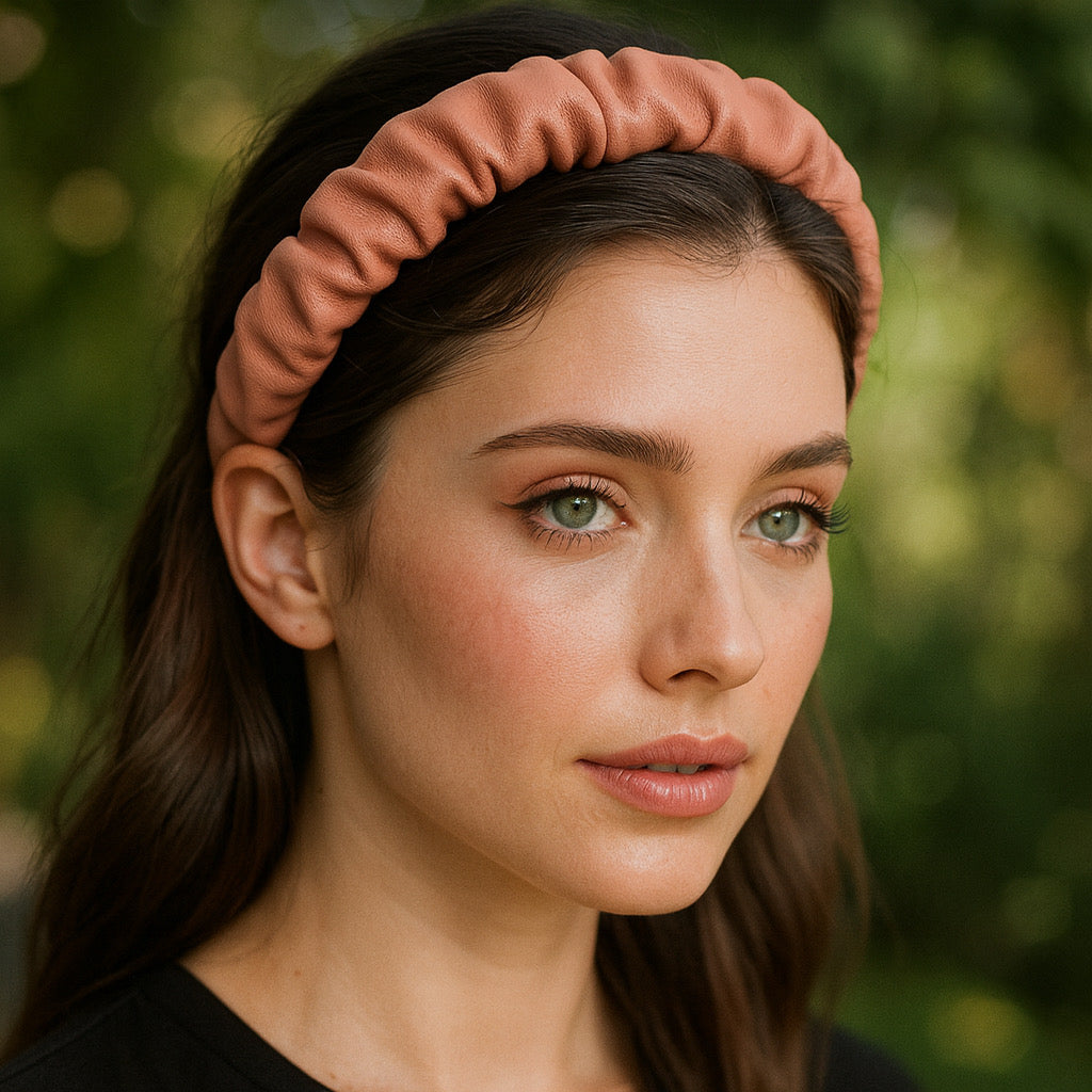 Model wearing PaulaB pink PU leather ruched headband with greenery background.