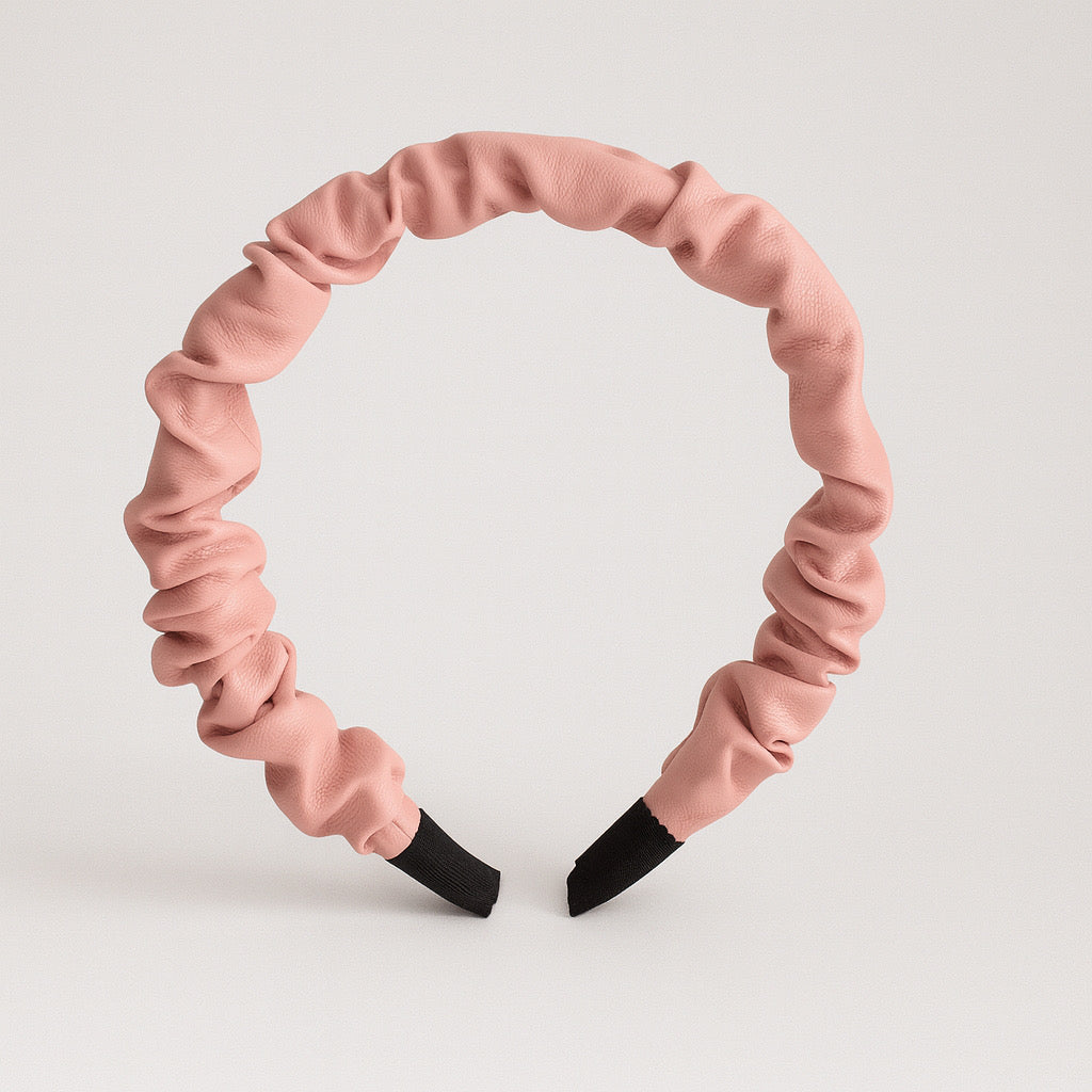 Standing display of PaulaB pink PU leather ruched headband on plain background.