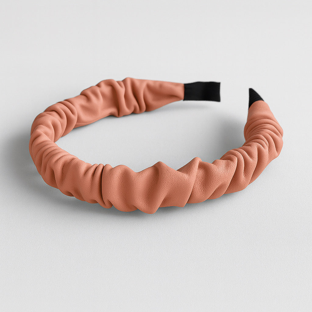 Flat lay of PaulaB pink PU leather ruched headband on neutral background.