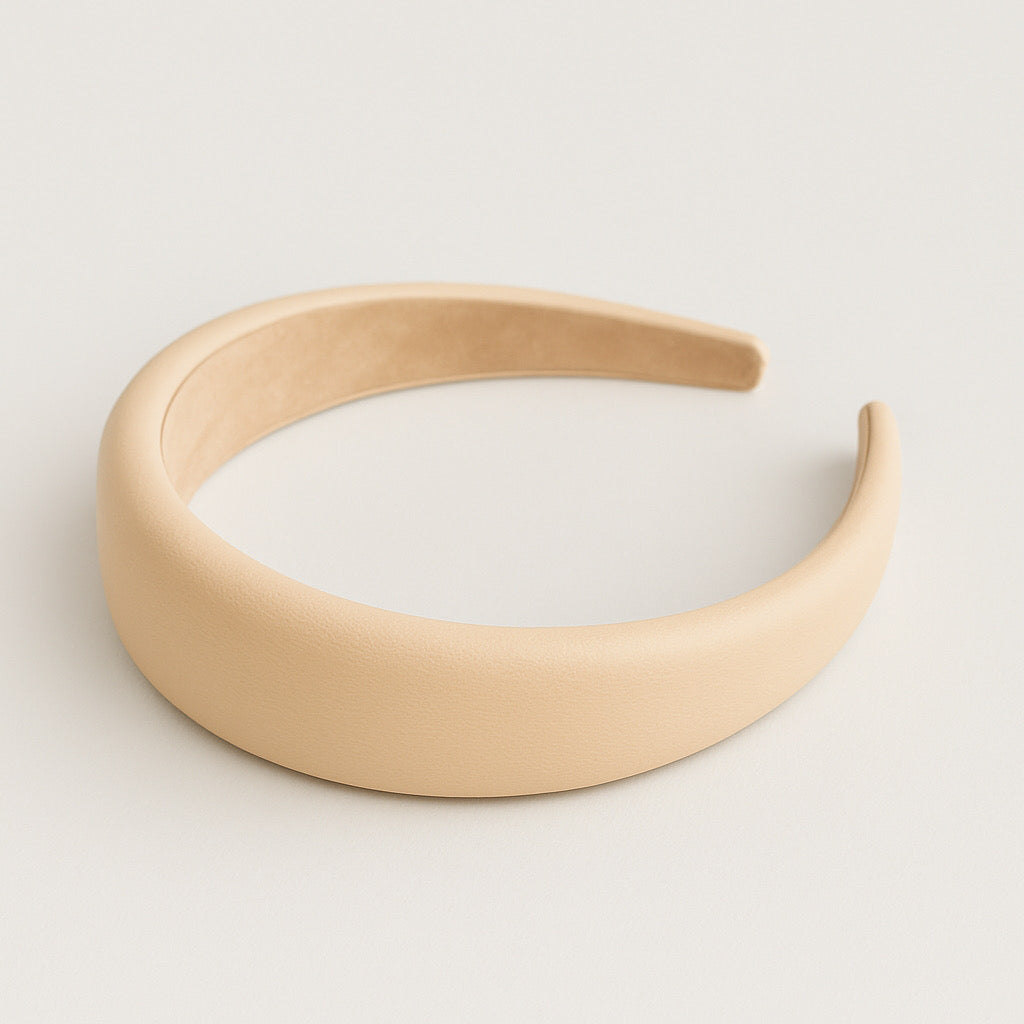 Flat lay of PaulaB nude PU leather padded headband with soft cushioned texture.