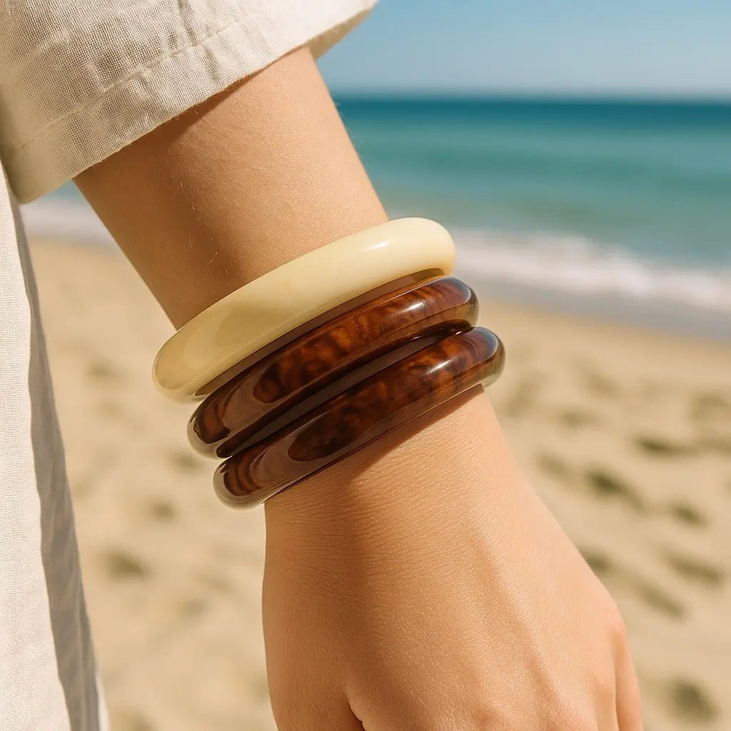 Lifestyle beach wrist shot of PaulaB resin bangles, 3-piece brown and cream bracelet set for women, coastal summer jewellery Australia NZ UK.