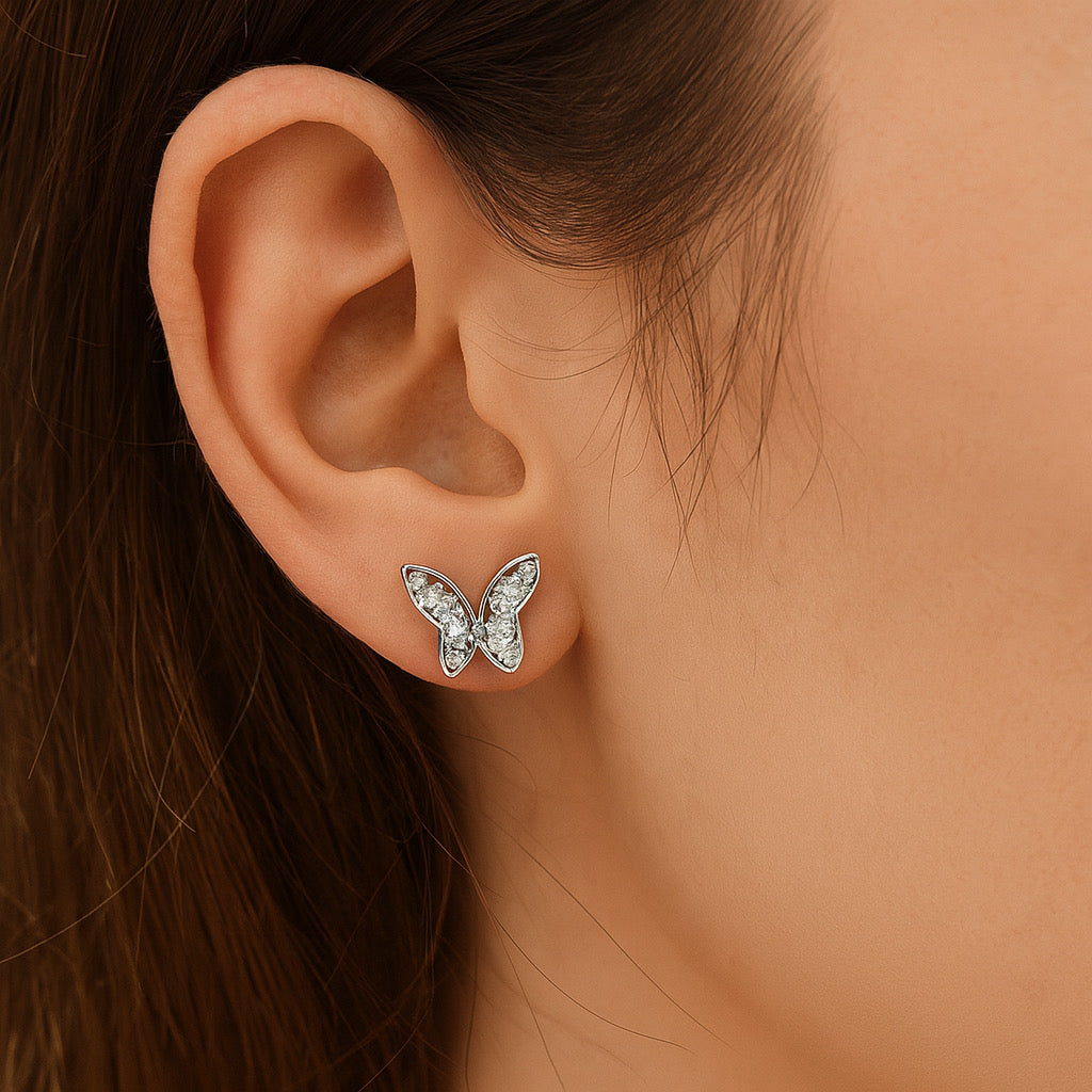 Close-up of PaulaB sterling silver rhodium plated butterfly earrings worn on ear, shimmering crystal details.
