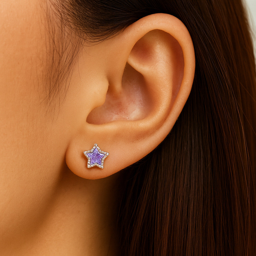 Close-up of model's right ear earing PaulaB sterling silver rhodium-plated star stud earrings with purple cubic zirconia stone.