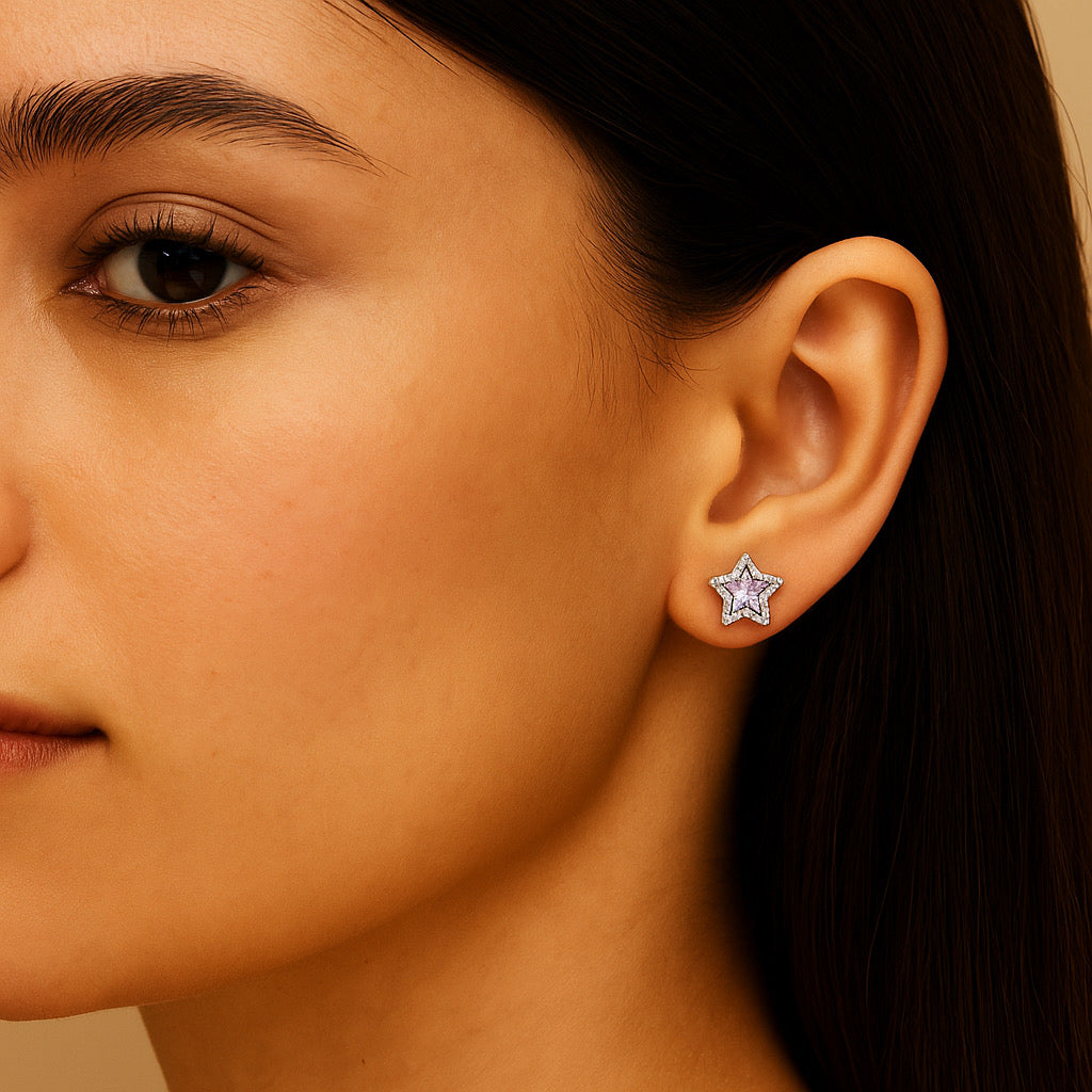 Model wearing PaulaB sterling silver rhodium-plated star stud earrings with light purple stone, close-up left ear.