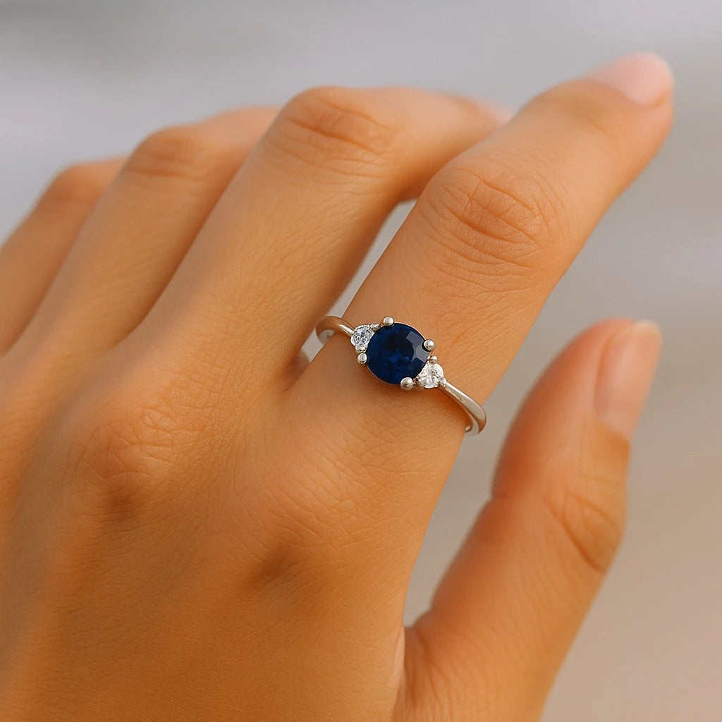 Adjustable sterling silver sapphire ring from PaulaB shown on model's hand at the beach, featuring deep blue gemstone and CZ accents, designed for Australia, NZ and UK coastal fashion markets.