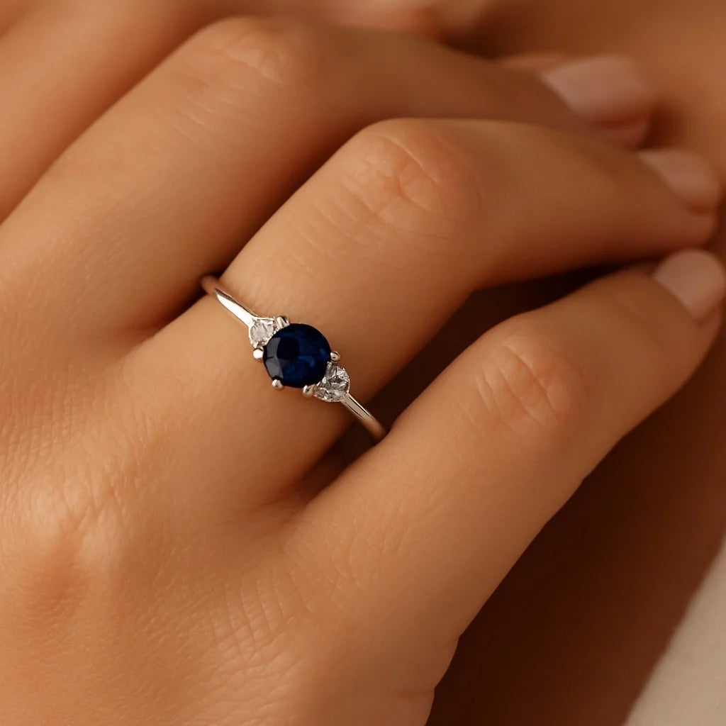 Model wearing PaulaB sterling silver adjustable ring with dark blue sapphire and cubic zirconia in a natural lifestyle hand pose. Perfect for Australia, NZ AND UK jewellery customers.