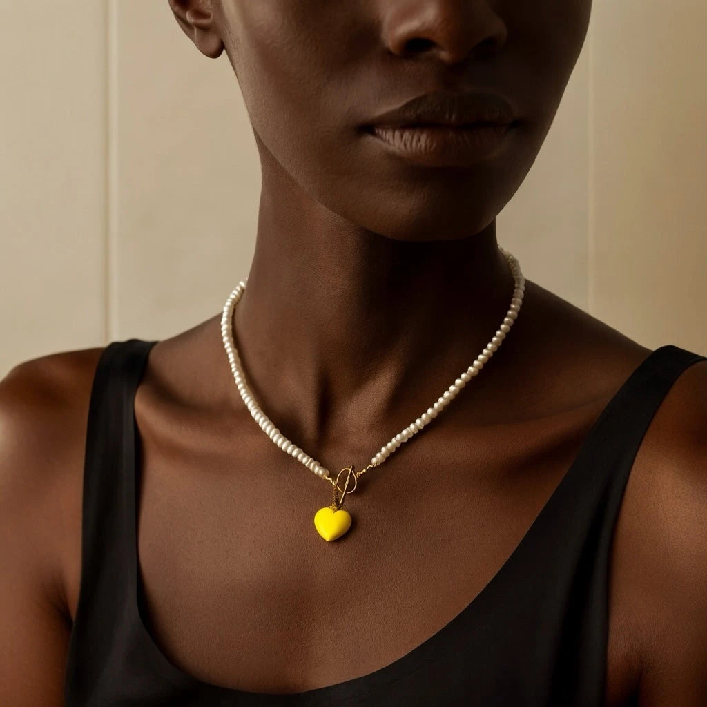 PaulaB Sunshine Yellow Heart Necklace displayed on model with dark skin tone, highlighting natural pearl texture and golden finish, Australia jewellery brand. 