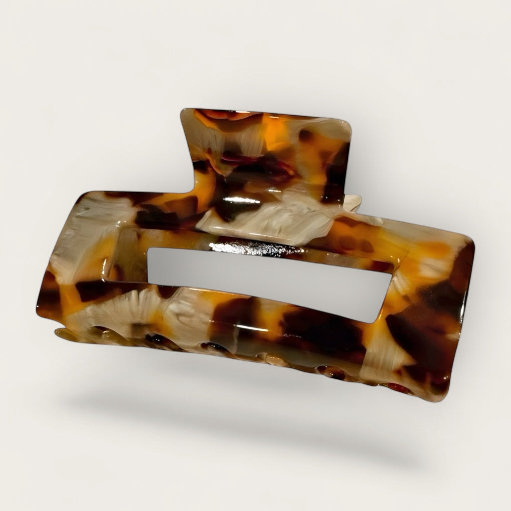 Tortoise sculpted hair claw clip flat lay on soft white, grey background.